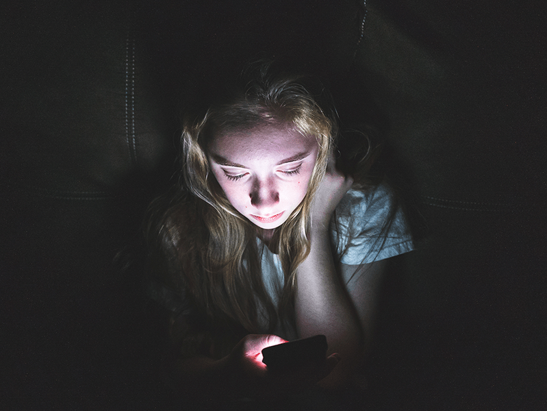 sad girl looking at her phone in the dark