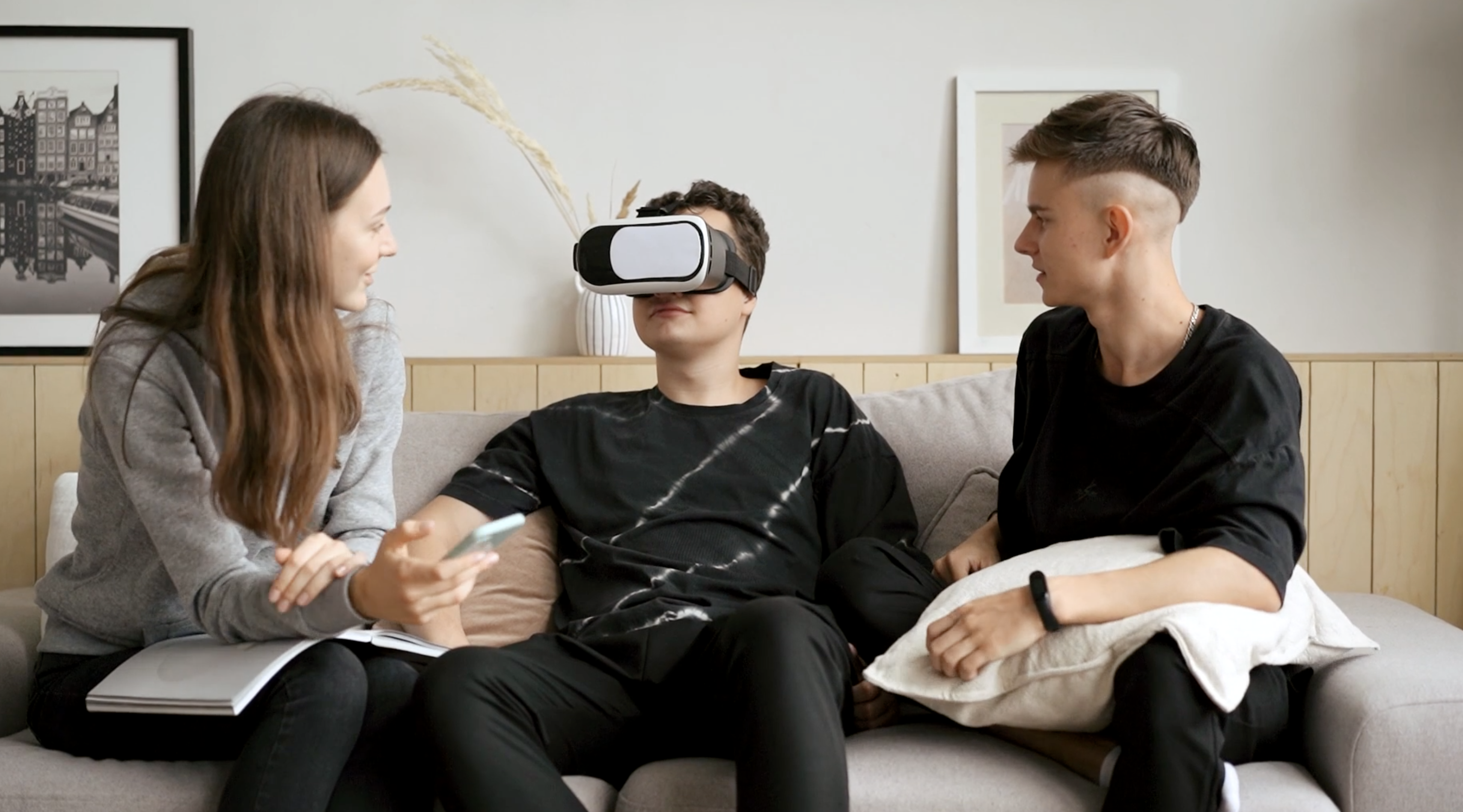 group of 3 young adults one wearing a VR headset